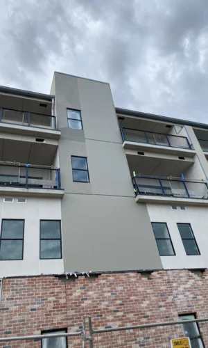 Professional painter applying cream exterior paint to a Blair Athol home facade